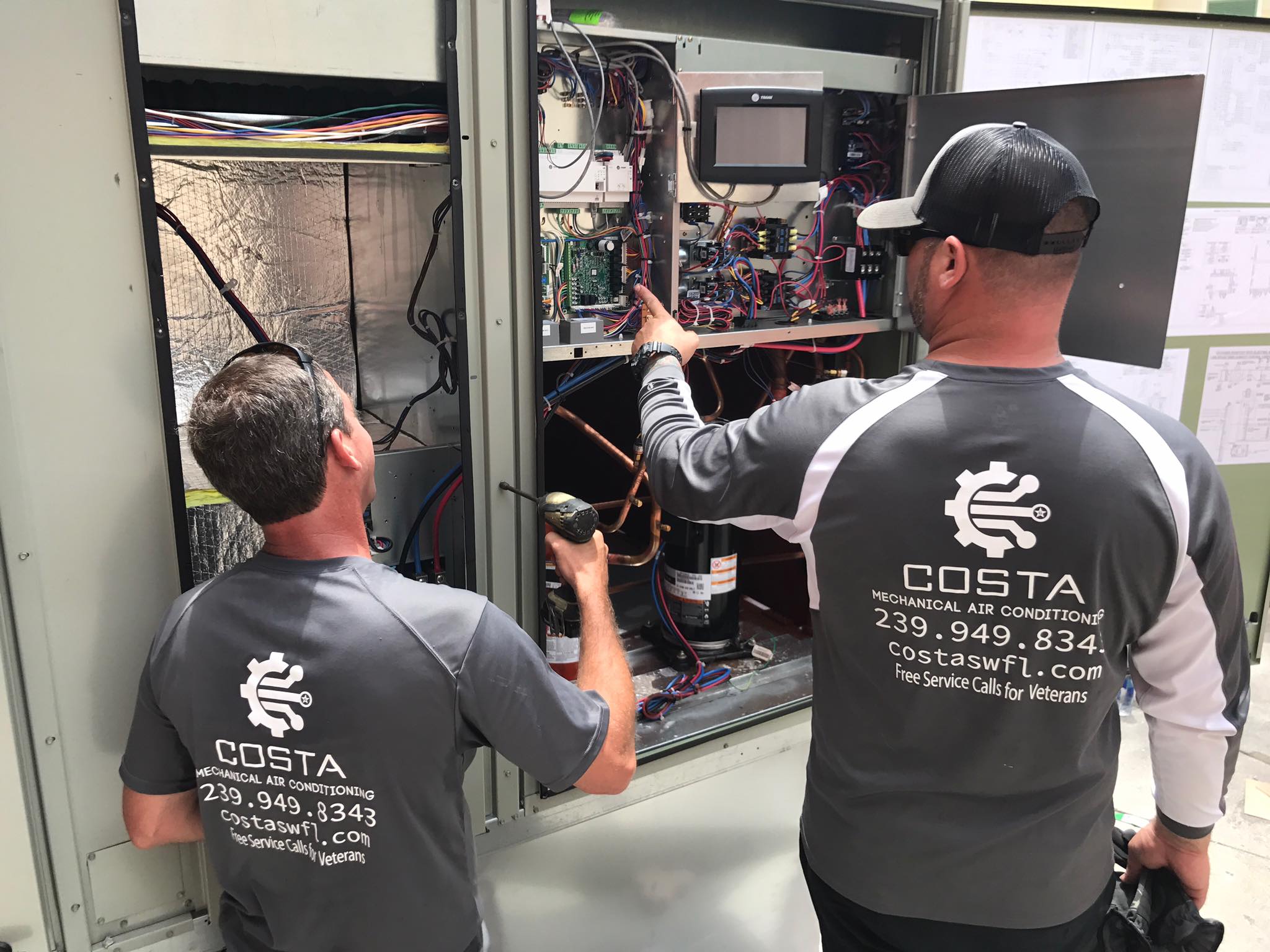 Costa Mechanical technicians in branded shirts servicing a commercial HVAC unit